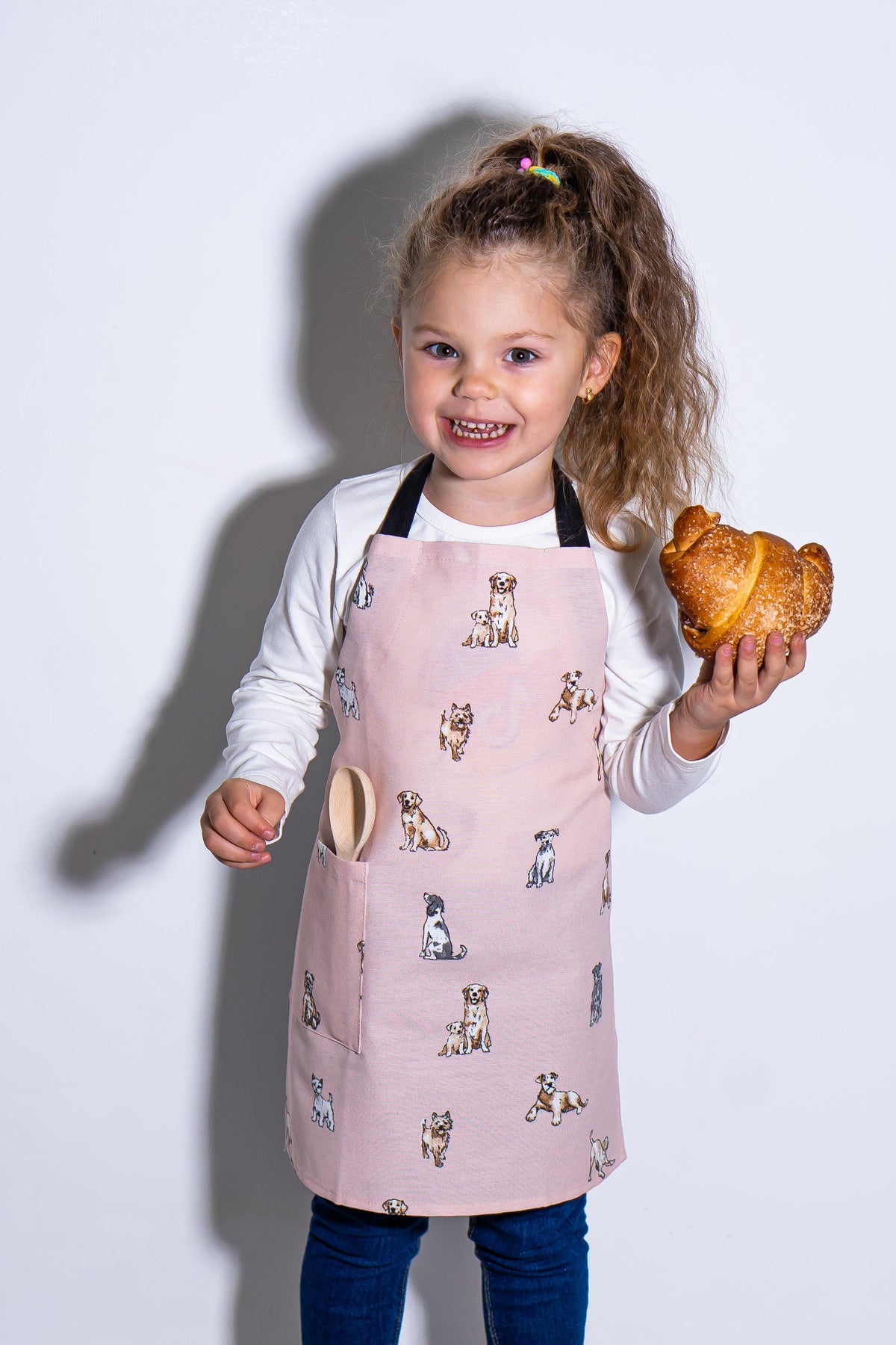 Dog print kids apron in blush, worn by a child