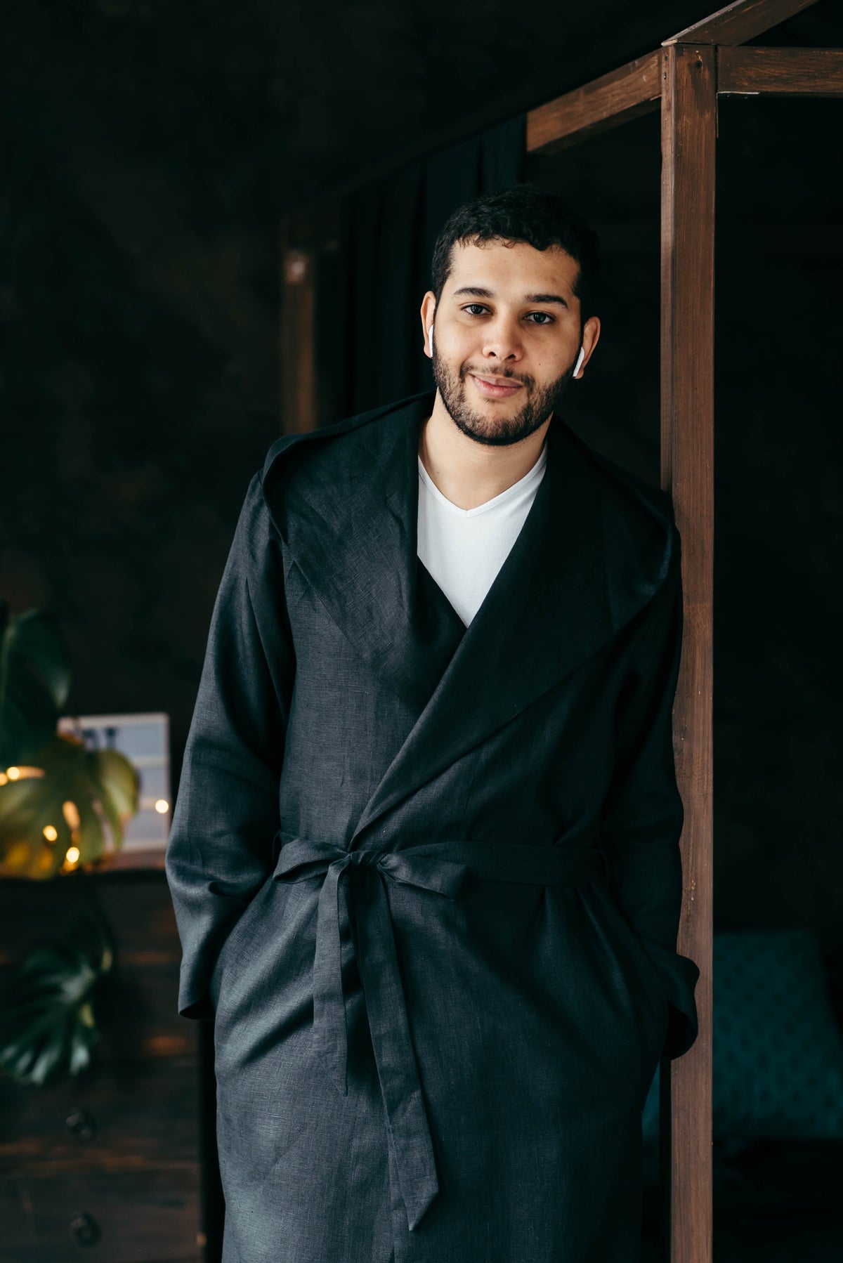 Man in a hooded linen robe by a window